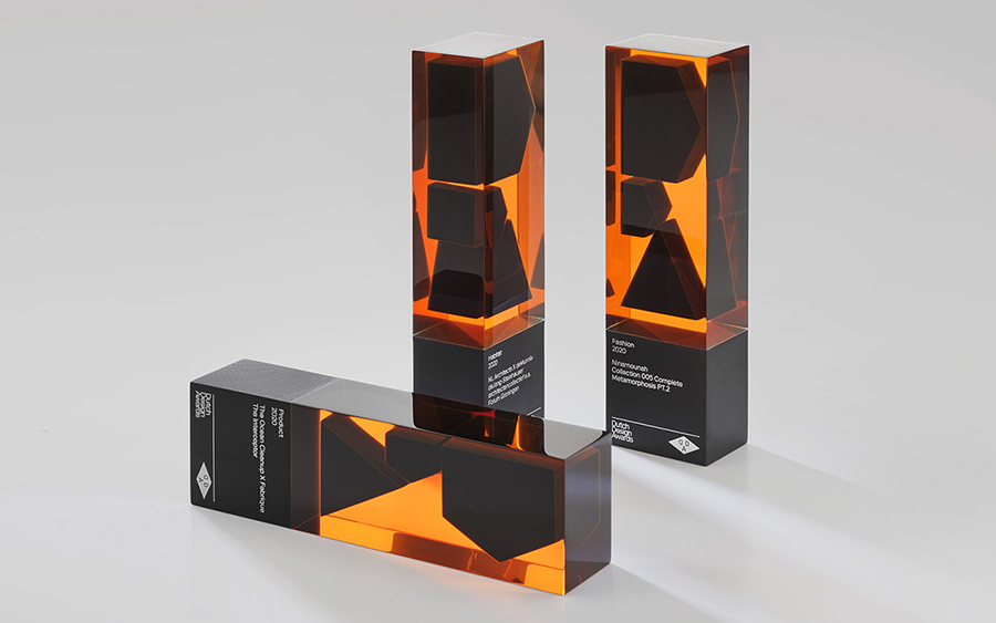 Deux trophées Dutch Design Awards, l'un debout et l'autre couché, au corps orange translucide et aux formes noires